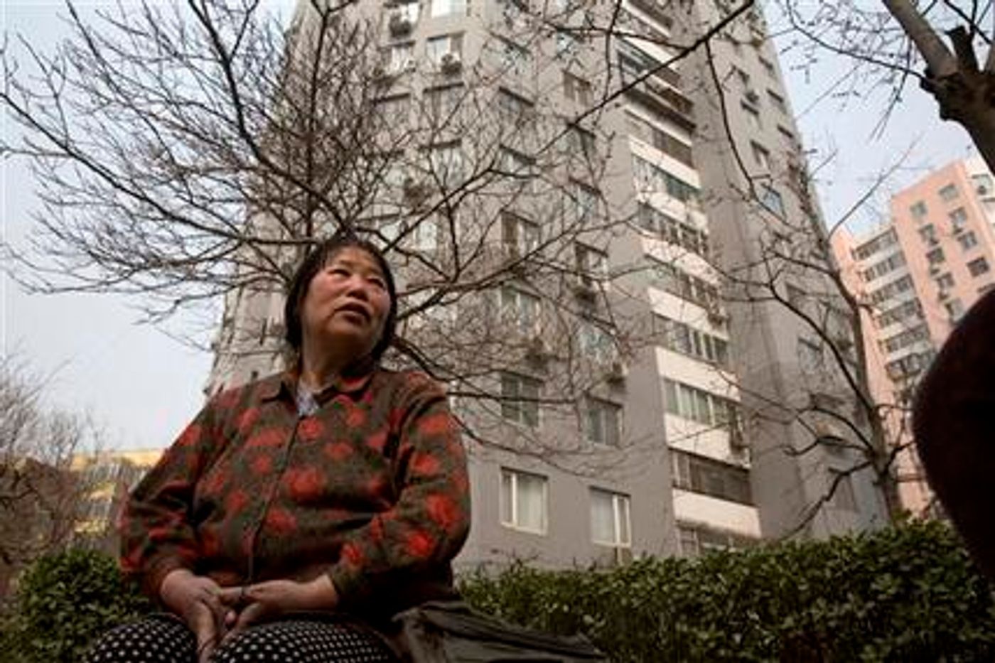 In this photo taken Monday, March 16, 2015, Chen Shuhong is interviewed in front of the residential compound where she rents out apartments as housing for cancer patients in Beijing. These so-called cancer hotels that dot the neighborhood around China's most renowned cancer hospital, give patients an affordable, cozy place to wait for appointments and undergo outpatient treatment.