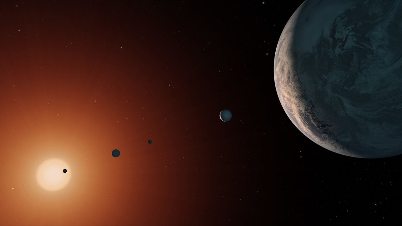 An artist's rendition of the TRAPPIST-1 system, in which seven Earth-like exoplanets orbit an ultra-cool red dwarf star at the center.