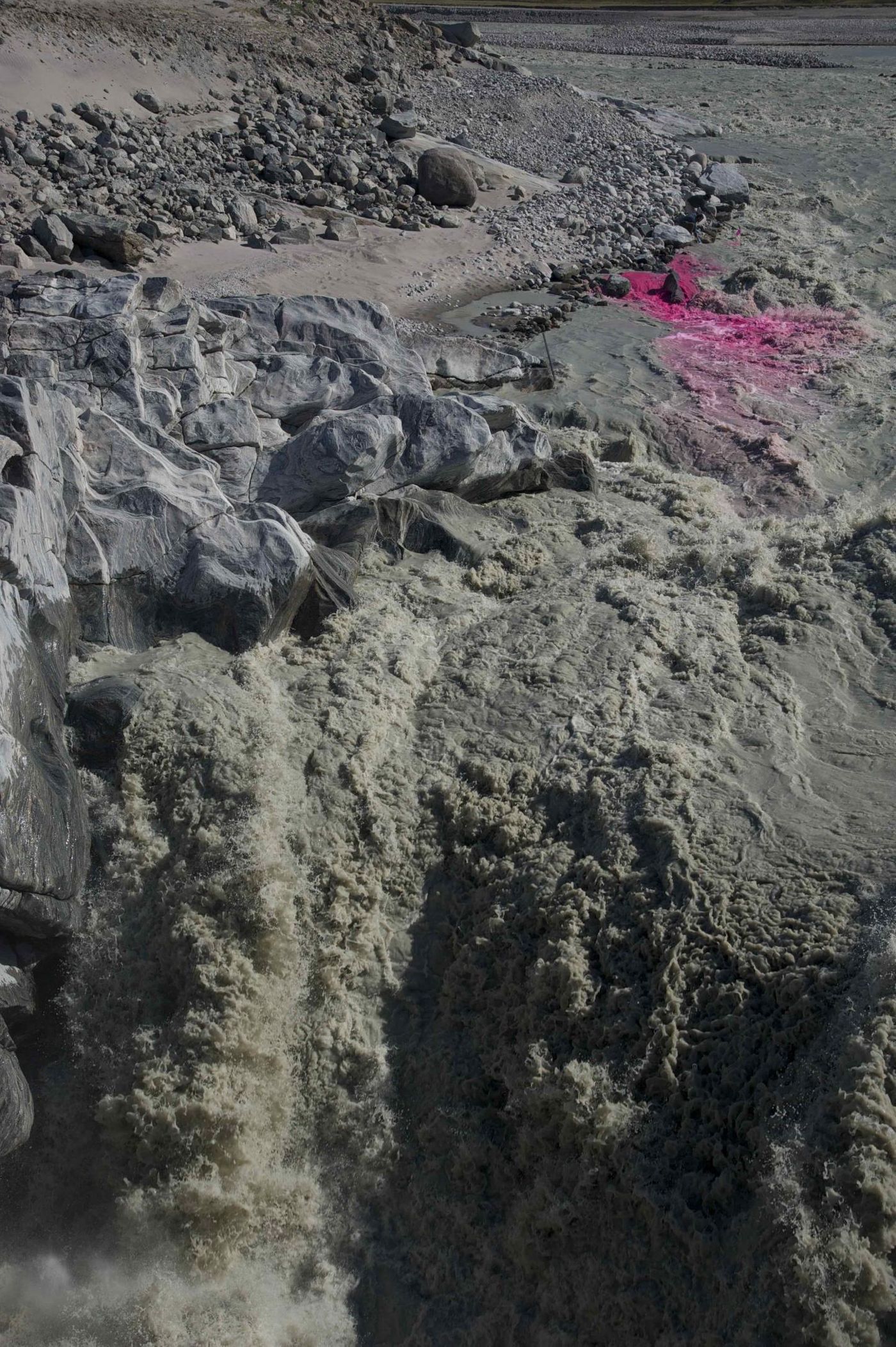 This photo shows a rhodamine dye injection into the proglacial river, just before a waterfall. The pink dye (the rhodamine) is used to calculate the water discharge of the proglacial river (i.e. how much water/melt if flowing in the river at that time). / Credit: Jakub D Zarsky