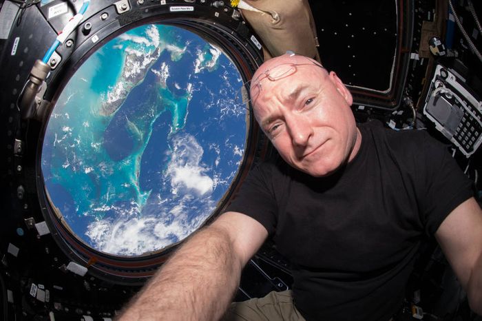 Scott Kelly poses for a selfie in space with the Earth in the background.