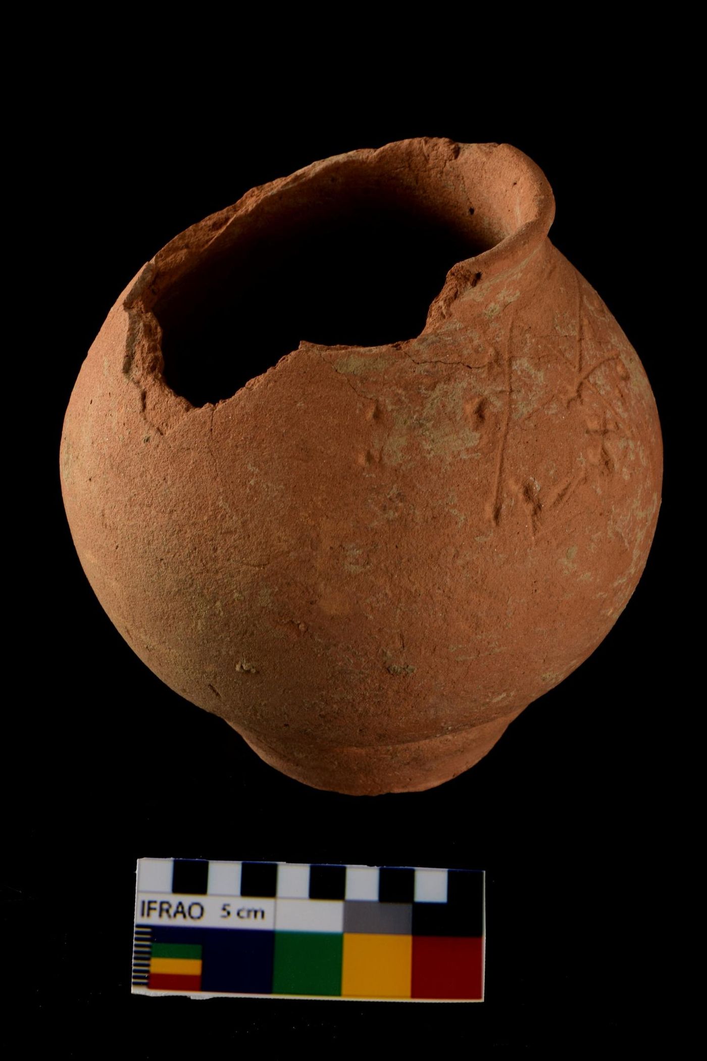This is a photograph of a red slipped ware globular pot placed near the head of the skeleton that yielded ancient DNA. There are lines as well as indentations on the upper right side, just below the rim. The indentations on the body of the pot could be examples of ancient graffiti and/or "Indus script". / Credit: Vasant Shinde / Deccan College Post Graduate and Research Institute