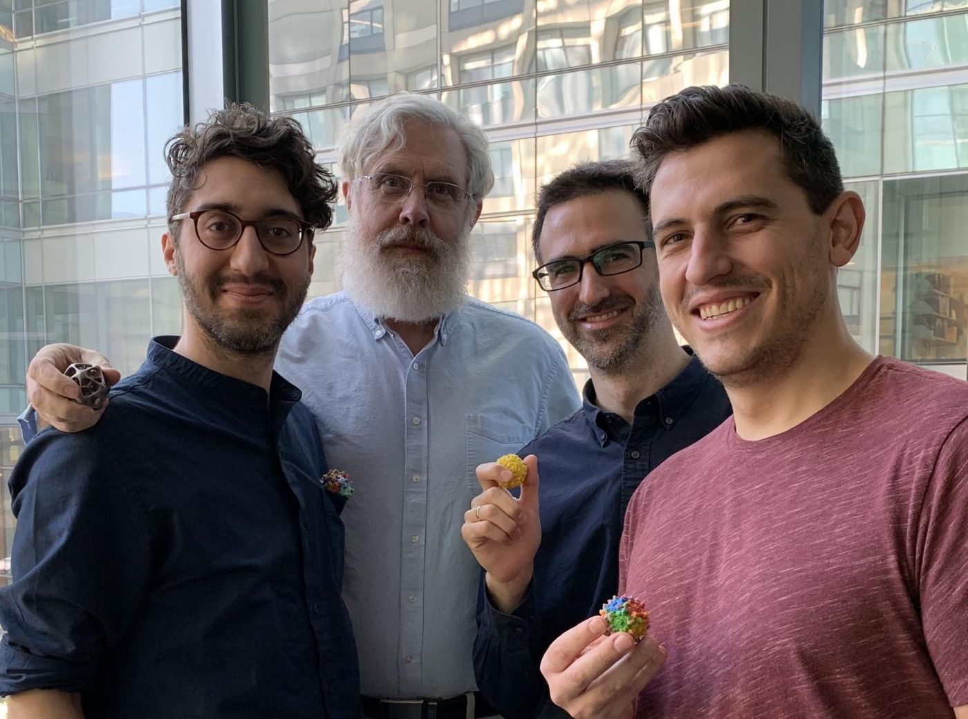 In this photo Sam Sinai, George Church, Eric Kelsic, and Pierce Ogden are holden small models of the AVVs capsid in their hands. / Credit: Wyss Institute at Harvard University