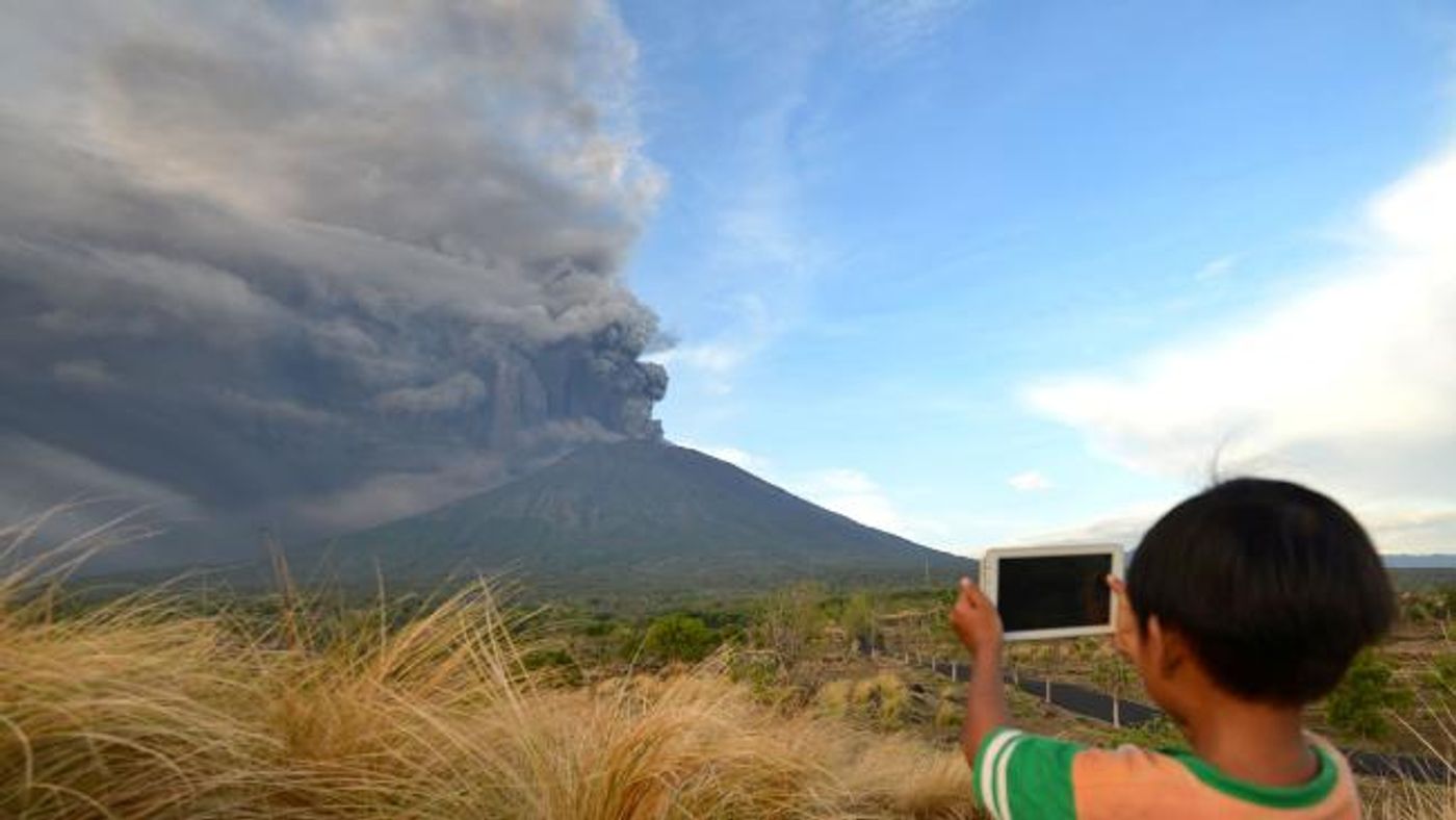 A young boy snaps a shot of the ash coming from Mount Agung. Photo: The Australian