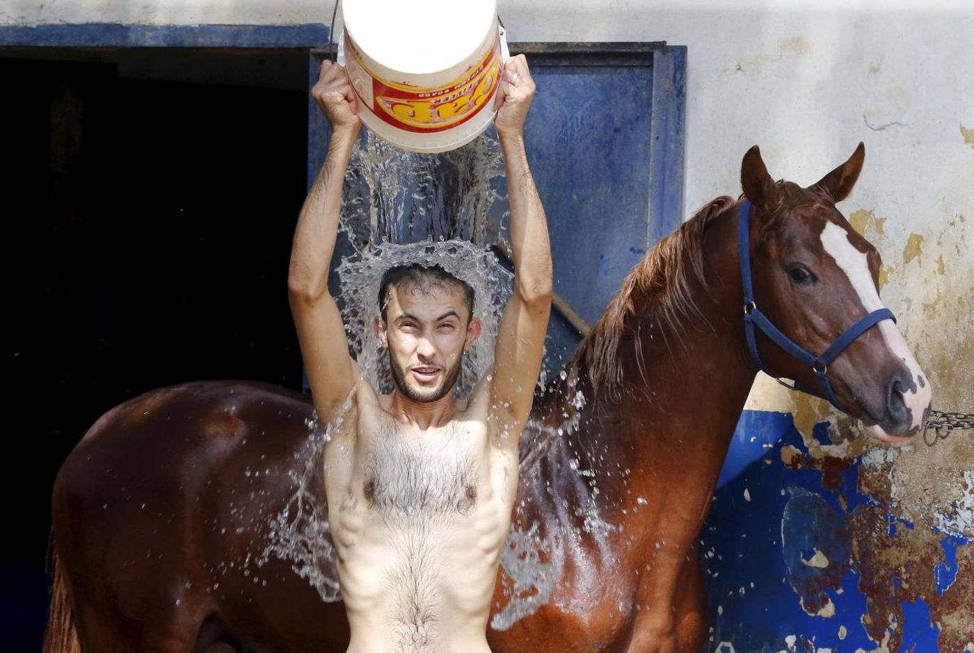 A man pours water over himself while washing a horse in order to cool it down as part of measures taken to ease the effect of a heatwave at the Beirut Hippodrome, Lebanon REUTERS/Mohamed Azakir