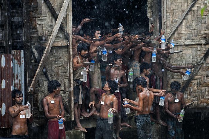 Bangladeshi and Rohingya migrants who were found drifting at sea collect rain water at a temporary shelter in Myanmar's northern Rakhine state. Photo: AFP