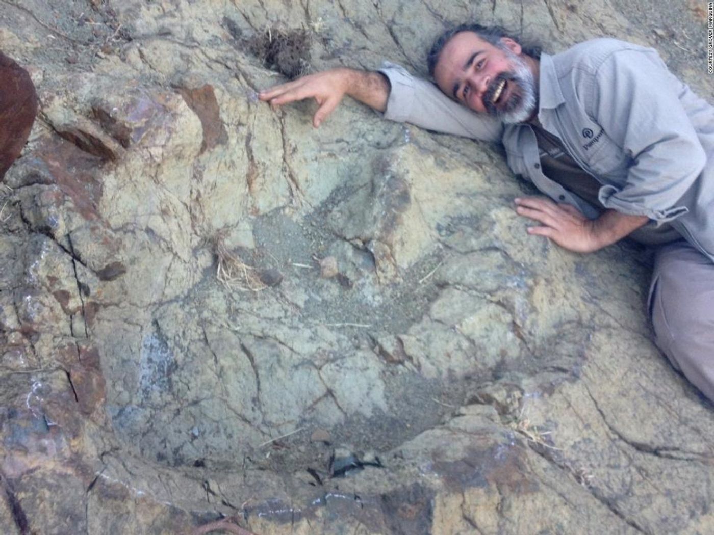 Scientist Sebastian Apesteguia poses for a photo next to the massive footprint.