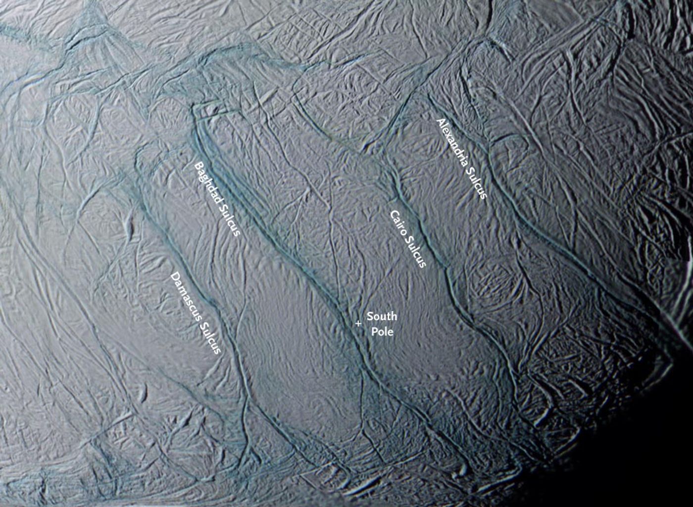 A closeup of the four 80-mile-long rifts(dubbed "tiger stripes") near Enceladus's south pole (white cross). These are the source of its gas-and-particle plumes. Blue tints in this false-color view from Cassini indicate an icy surface covered with coarse grains and boulders. (Credit: NASA/JPL/Space Science Institute/CICLOPS)