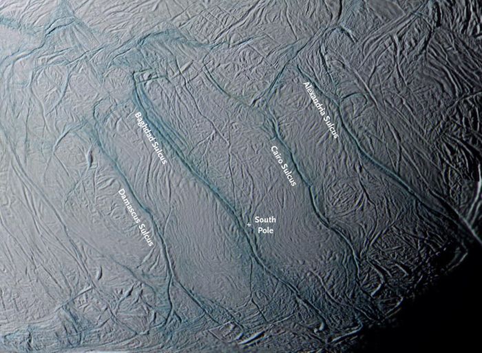 A closeup of the four 80-mile-long rifts(dubbed "tiger stripes") near Enceladus's south pole (white cross). These are the source of its gas-and-particle plumes. Blue tints in this false-color view from Cassini indicate an icy surface covered with coarse grains and boulders. (Credit: NASA/JPL/Space Science Institute/CICLOPS)