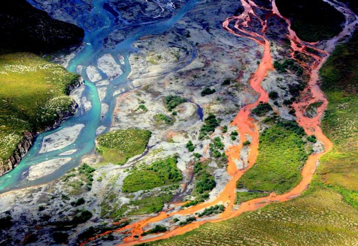 An aerial view of the rust-colored Kutuk River in Gates of the Arctic National Park in Alaska. Thawing permafrost is exposing minerals to weathering, increasing the acidity of the water, which releases metals like iron, zinc and copper.  Credit:  Ken Hill / National Park Service