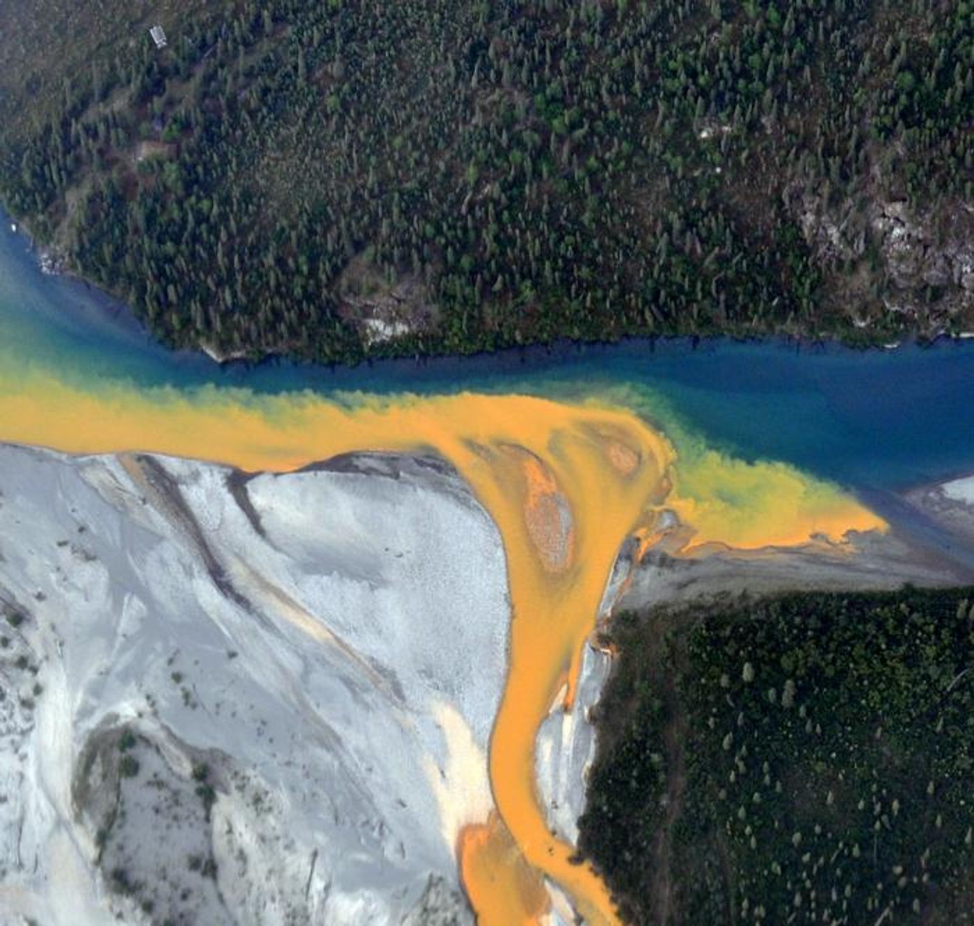 An aerial view of the Kutuk River in Alaska's Gates of the Arctic National Park that looks like orange paint spilling into the clear blue water.  Credit:  Ken Hill / National Park Service