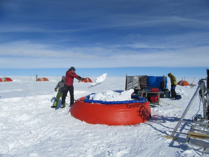 Ian McDowell throws snow into a pool where it will be melted and used to drill a hot water borehole in Greenland during his M.S. research in 2018. (Credit: Ian McDowell)