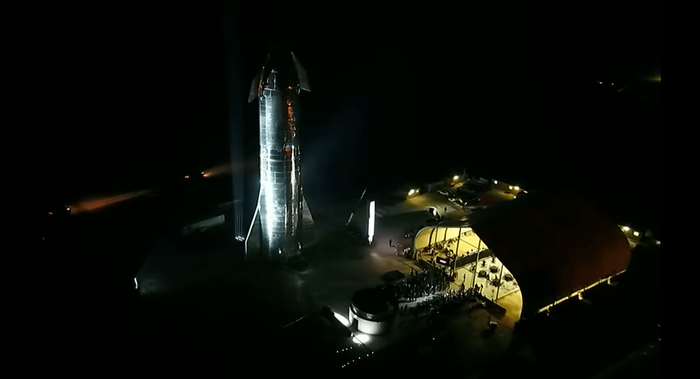 SpaceX's Starhopper spacecraft stands tall behind a stage where Elon Musk talked about the company's future endeavors.