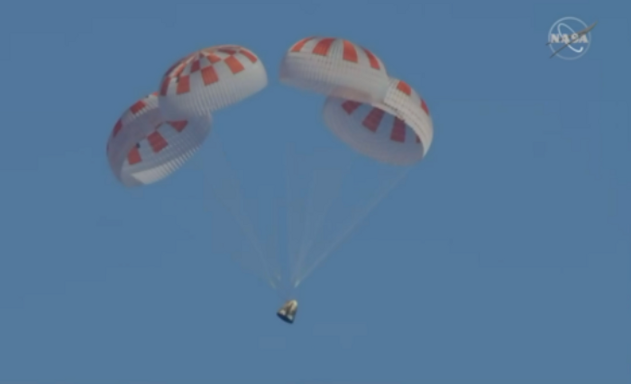 A photograph of SpaceX's Crew Dragon capsule falling from the sky with parachutes.