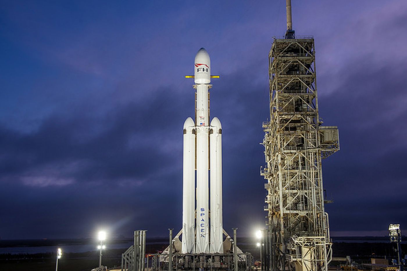 A night shot of the SpaceX Falcon Heavy rocket standing upright at NASA's launchpad 39A.