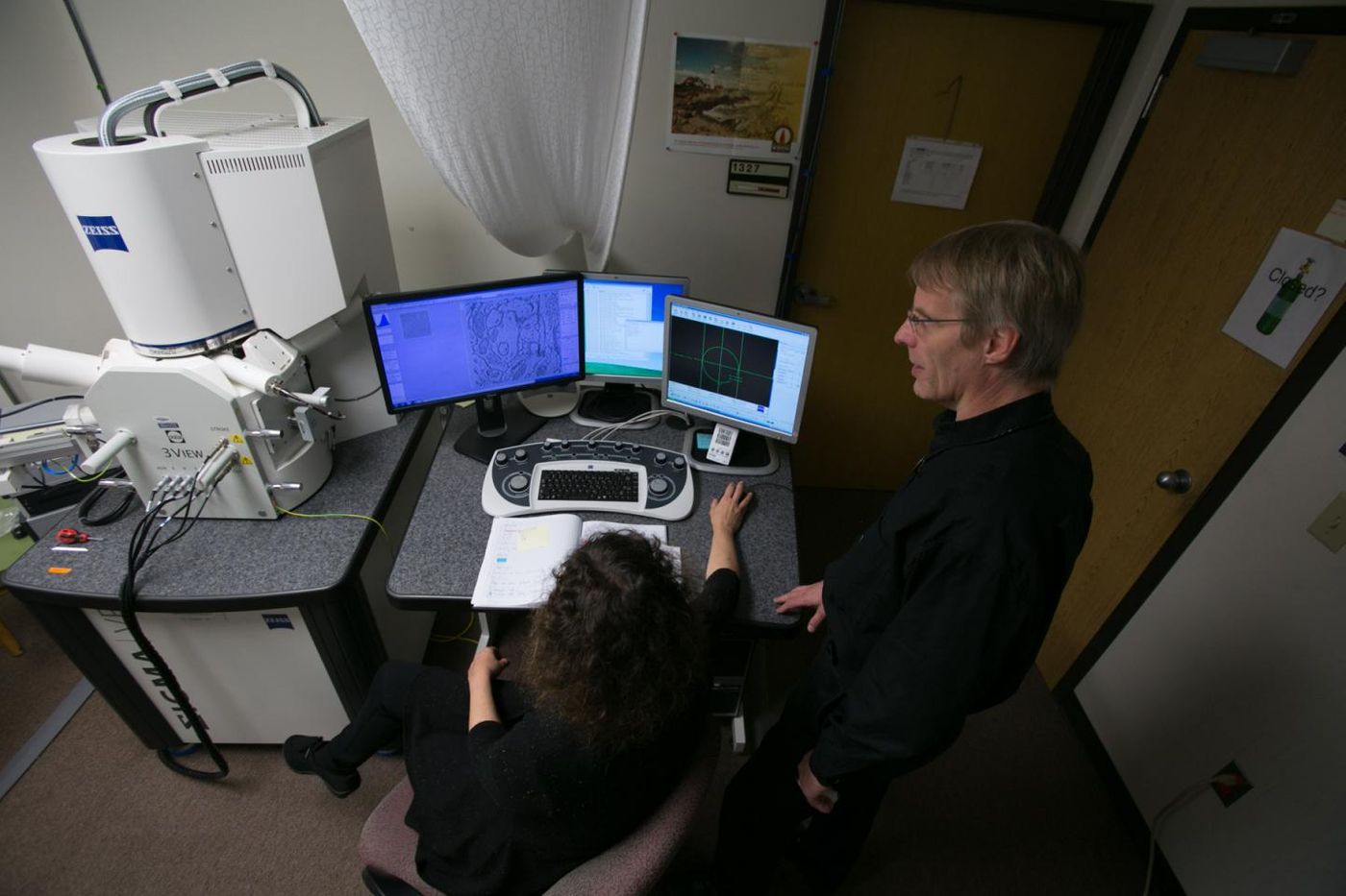 Drs. Cirelli, foreground, and Tononi, right, study an image of a mouse brain taken by a scanning electron microscope, left. Thousands of these images were analyzed for the study published this week in the journal Science. / Credit: John Maniaci/UW Health