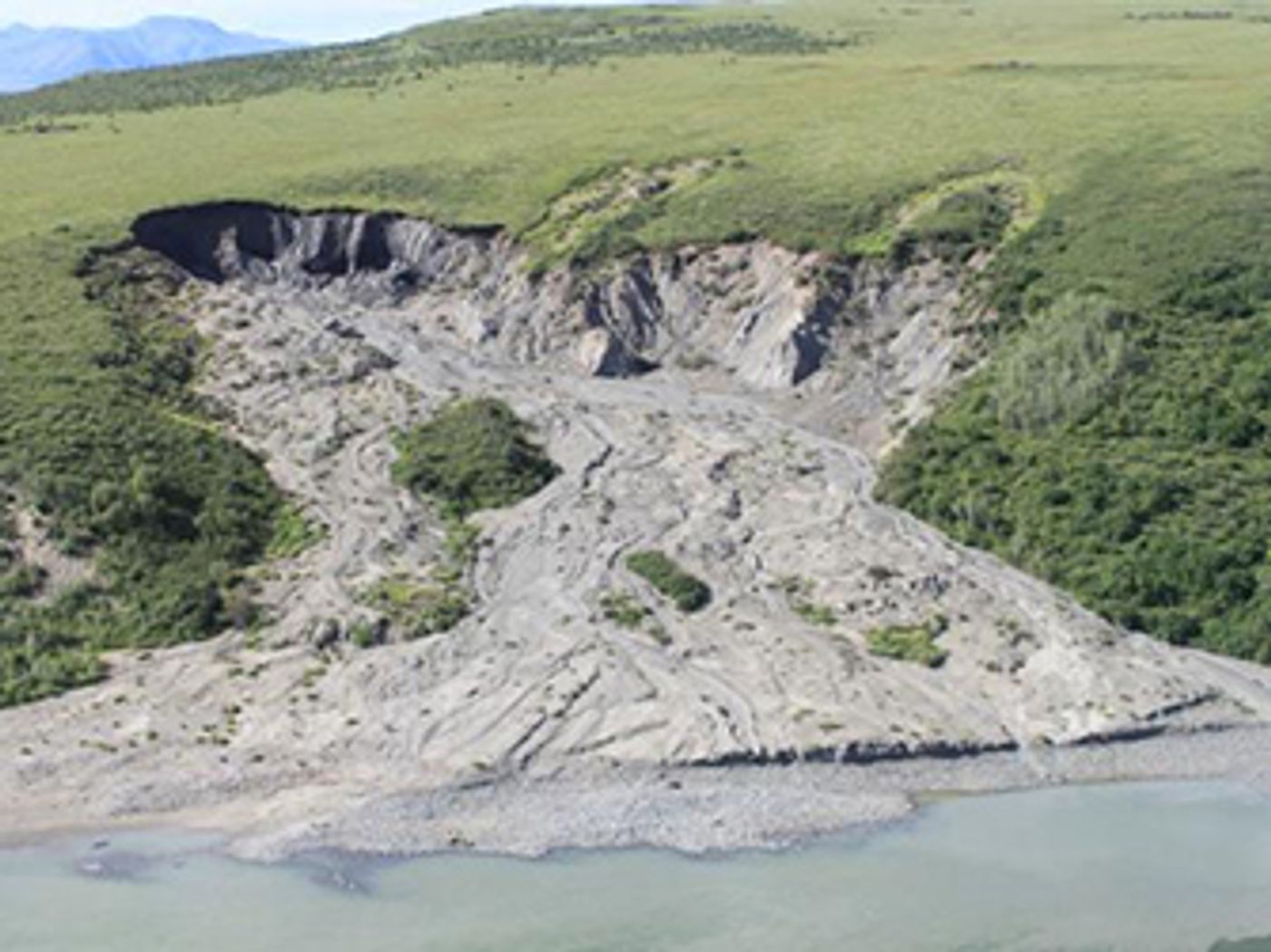 A retrogressive thaw slump where the top layer of usually frozen soil has melted and slid into the river below. / Credit: NPS Photo.