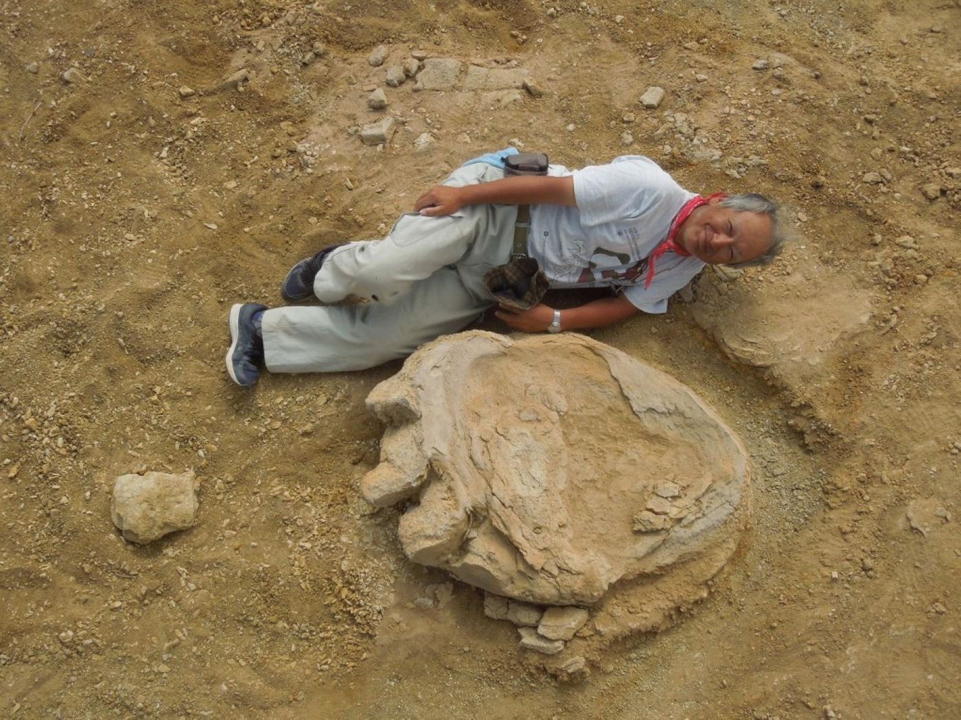Professor Shinobu Ishigaki of the Okayama University of Science poses next to the large dinosaur footprint. 