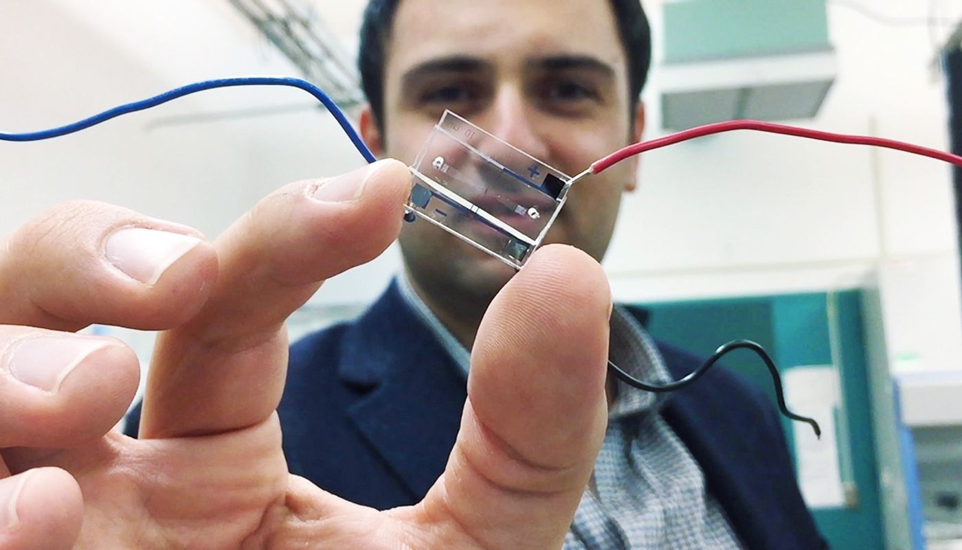 Fatih Sarioglu holds a hybrid microfluidic chip that uses a simple circuit pattern to assign a unique seven-bit digital identification number to each cell passing through the channels.