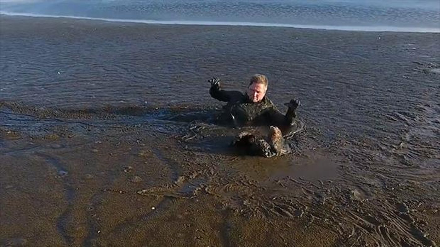 A photographer drags himself through a pit of thick mud to rescue a stuck white-tailed eagle.