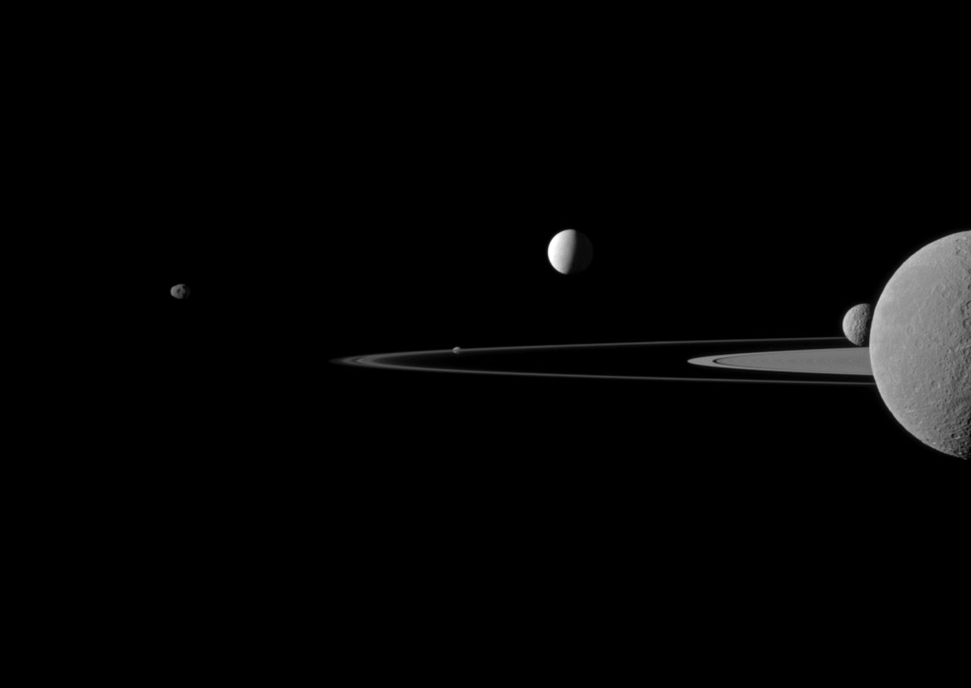 An image taken by the Cassini spacecraft of some of Saturn's moons orbiting the planet.