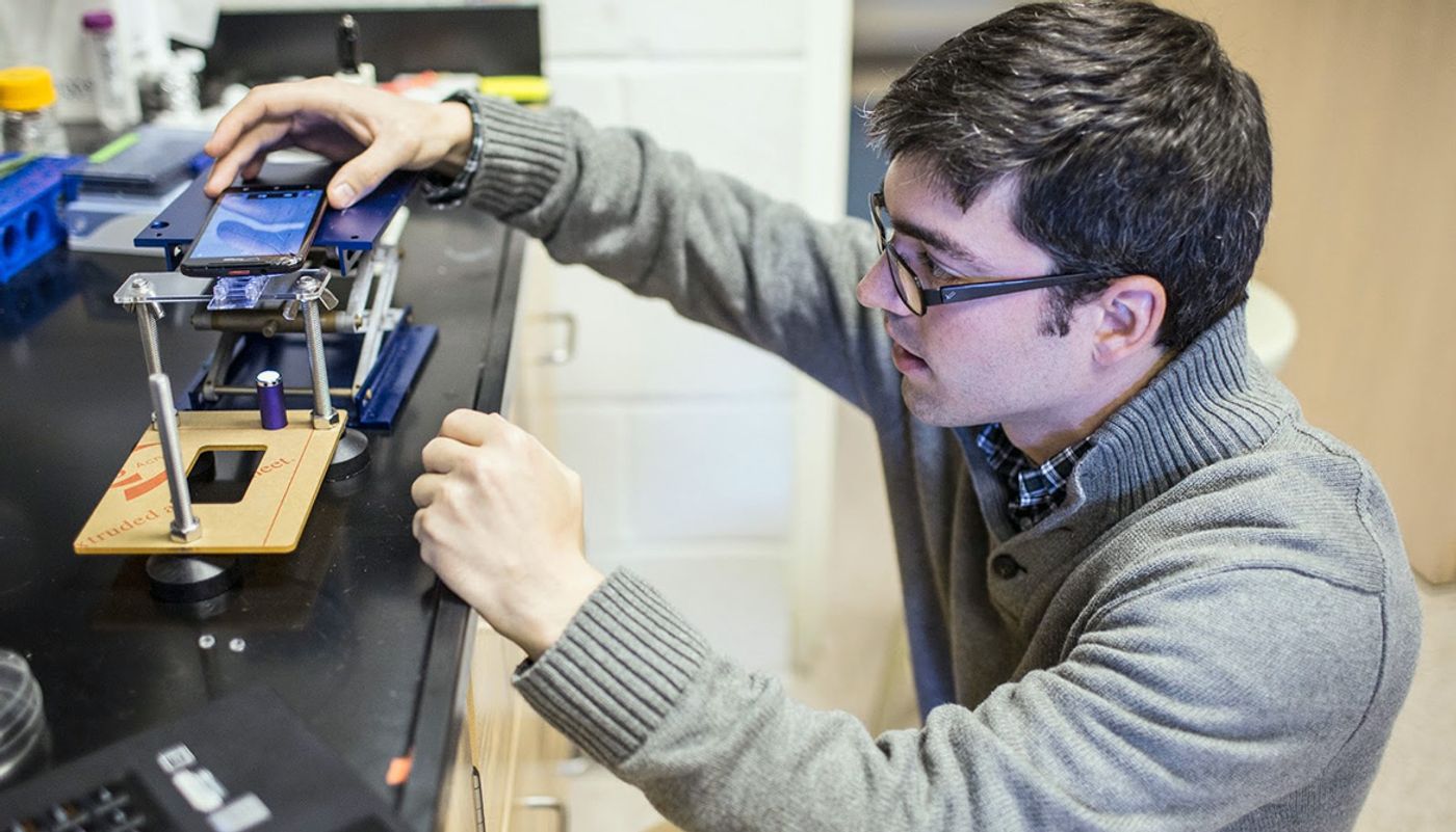 Kevin Yehl sets up a smartphone microscope to get a readout for the particle motion of the rolling DNA-based motor.